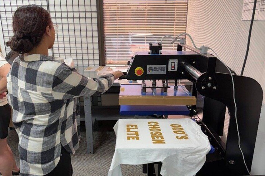 A person operating a machine with a white tablecloth labeled 'GOING GONE' in front of it. 1