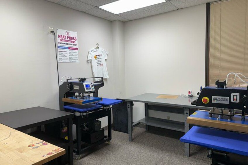 A heat press station in a workshop with a sign, a t-shirt, and a table. 4