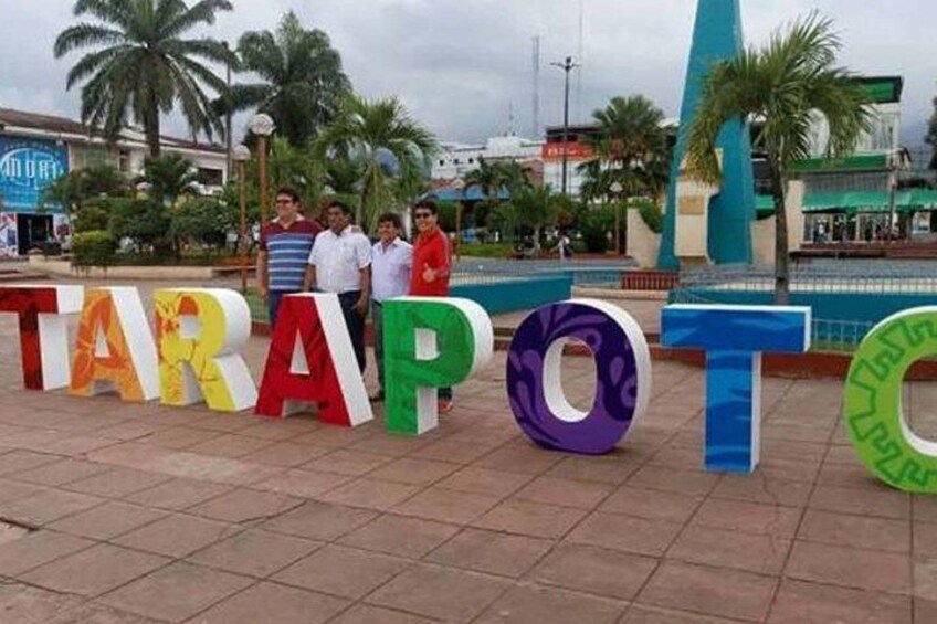 Large colorful letters spelling 'TARAPOT' on a paved surface with palm trees and buildings in the background. 4