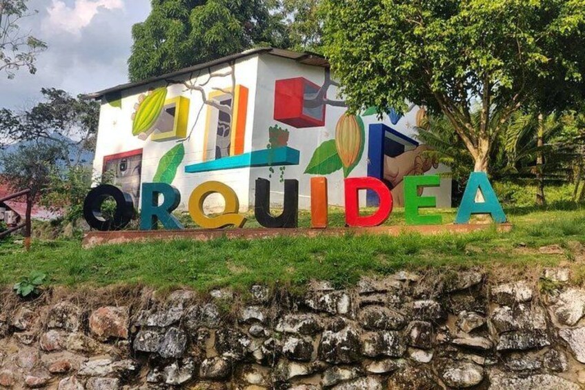 A colorful sign with the word 'ORQUIDEA' and a building in the background. 3