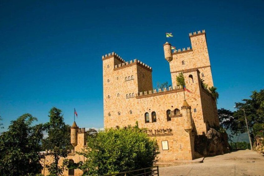 A large stone castle with two prominent towers, a flag, and a clear blue sky. 1