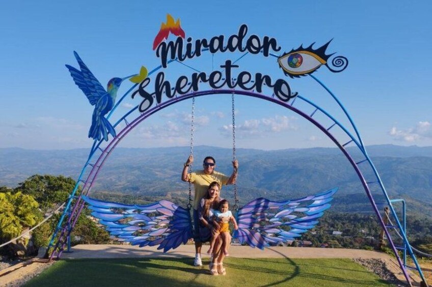 A swing ride with a sign reading 'Mirador Sheretano' and a scenic mountain backdrop. 5