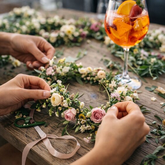 Manos disponiendo flores sobre una mesa con una bebida en un vaso. 2