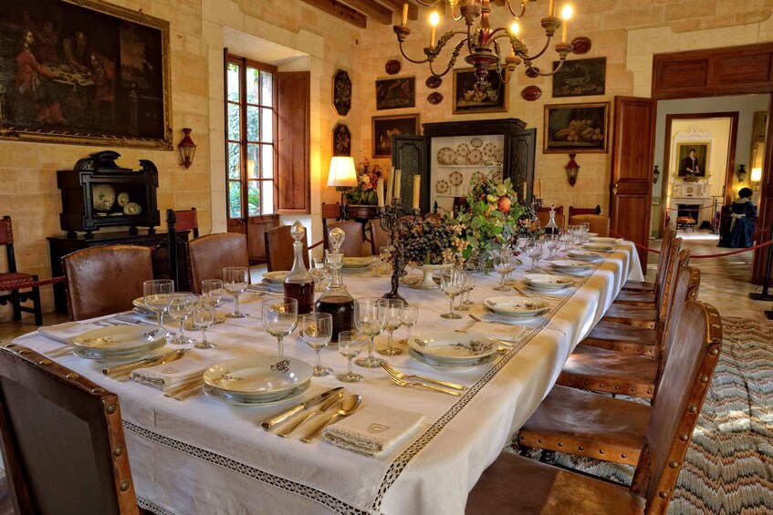 A long dining table set with fine china, silverware, and glassware, surrounded by wooden chairs. 3