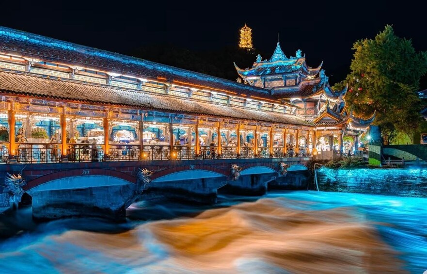 A traditional Chinese building with illuminated windows and a pagoda in the background. 2