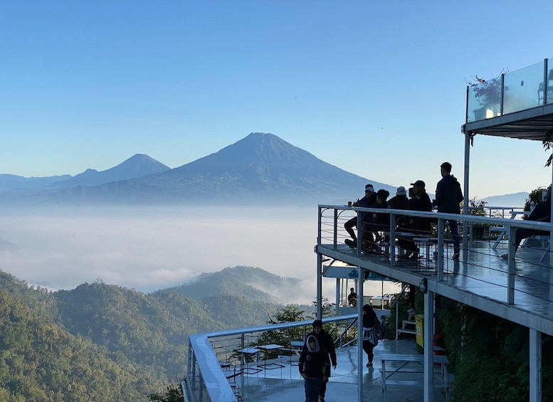 A group of people on a glass observation deck overlooking a mountain and a valley. 3