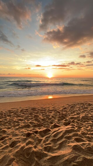 A beach with sand patterns and a sunset over the ocean. 4