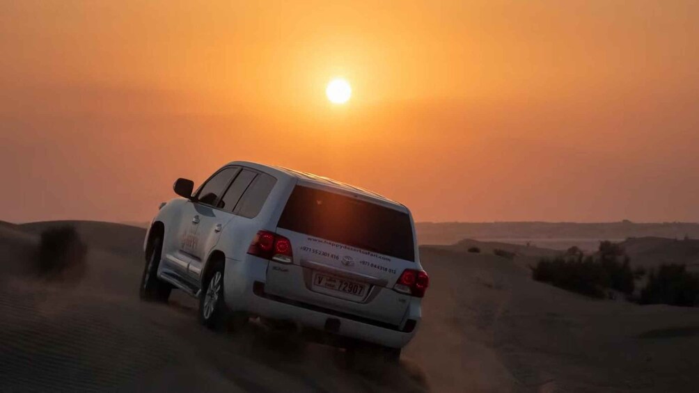 Un SUV bianco percorre una strada sterrata con un tramonto sullo sfondo. 4