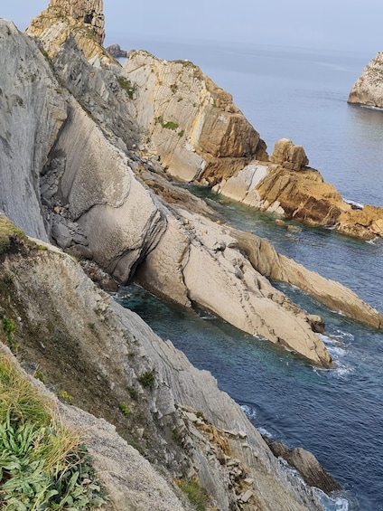A coastal landscape with rocky cliffs and clear blue waters. 4