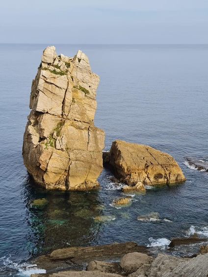 A rocky coastline with a prominent rock formation and clear blue water. 2
