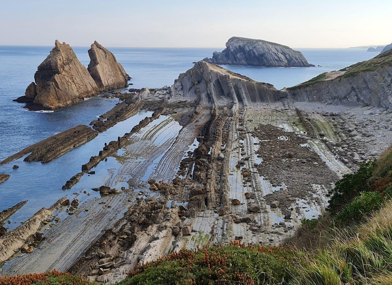 A coastal landscape with layered rock formations and cliffs. 1