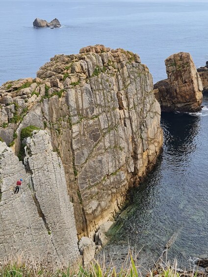 A rocky coastline with a person rock climbing. 3