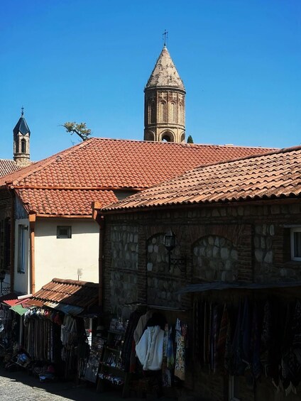 Un edificio in pietra dal sapore tradizionale, con tetto in tegole, un campanile e un mercato ricco di prodotti. 3