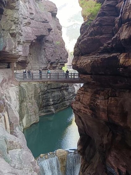 Un canyon rocheux avec une cascade et un pont en bois. 2