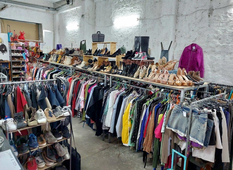 A clothing and shoe store with racks of clothes and shelves of shoes. 4