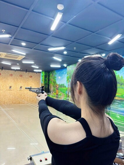 Una persona punta una pistola a un bersaglio in un poligono di tiro al chiuso. 3