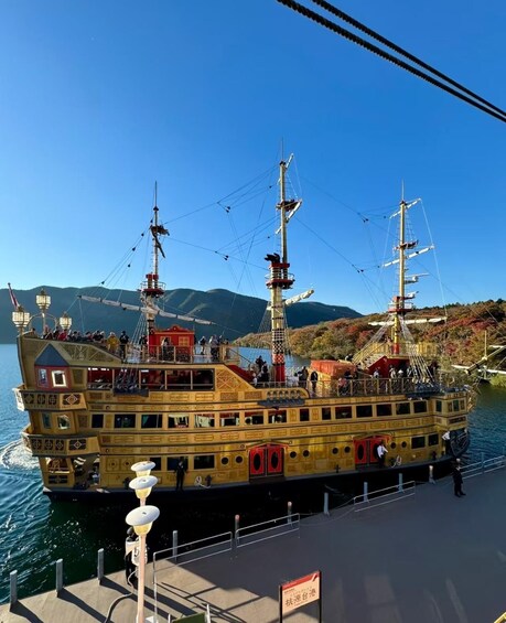 A large, ornate ship docked at a pier with a mountainous landscape in the background. 3
