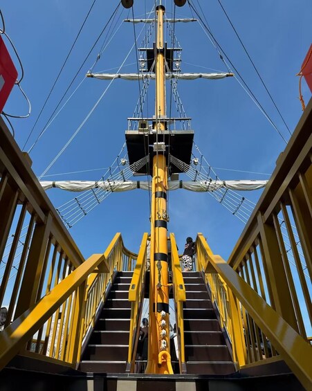 A ship's mast with rigging and a person climbing the stairs. 4