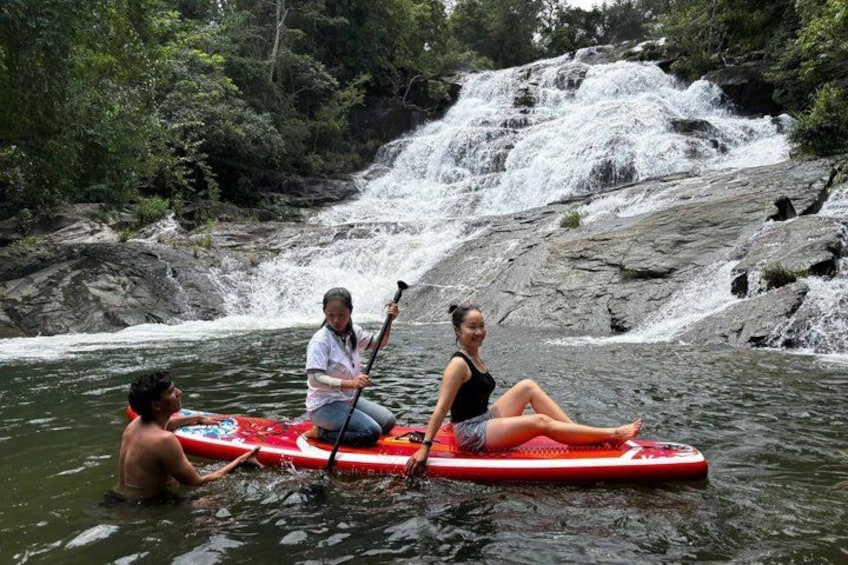 People on paddleboards in a river with a waterfall in the background. 4