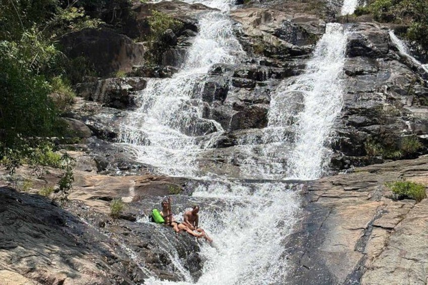 A waterfall cascading over rocks with two people sitting on the edge. 5