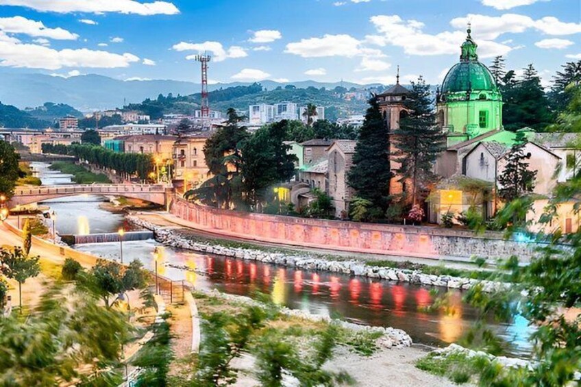 A river with a bridge, a green-roofed church, and a tower. 4