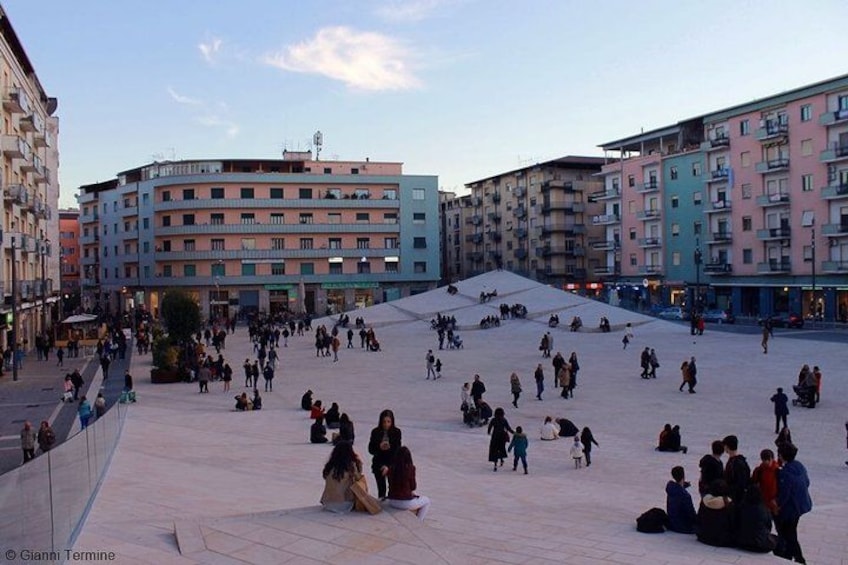 A public square with people sitting and walking. 1