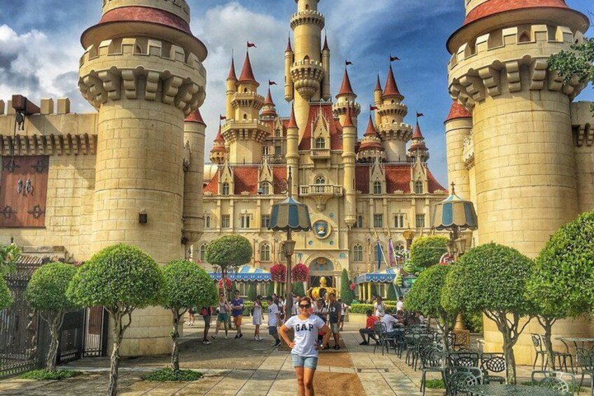 A castle-like structure with multiple towers and turrets, surrounded by neatly trimmed hedges and a paved walkway. 2