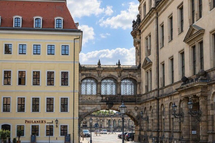 A street with historic buildings, an archway, and a sign for 'Paulaner's.' 5
