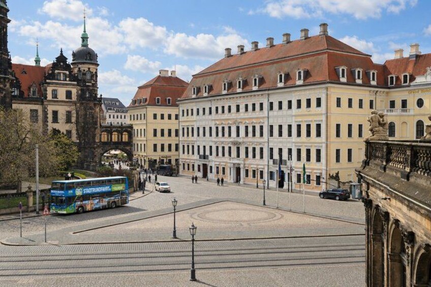 A historic city square with a double-decker bus, buildings, and a bridge in the background. 4