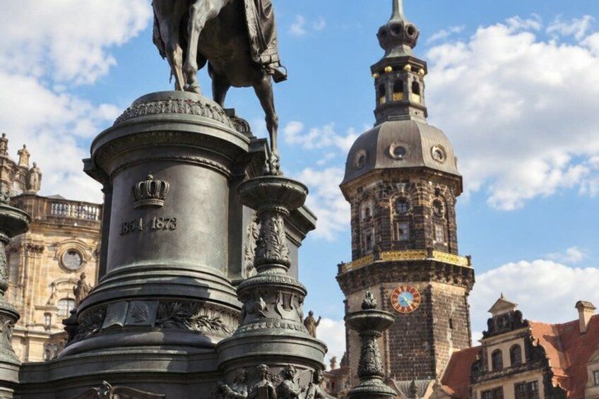 A historical monument with a horse statue, a clock tower, and intricate architectural details. 3