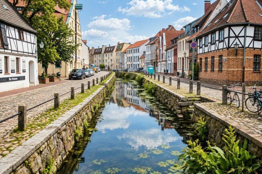 A canal with buildings on either side, a bicycle, and a clear sky. 2