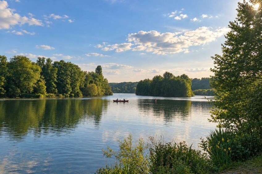 A calm lake with a small boat, surrounded by dense trees and a clear sky. 2