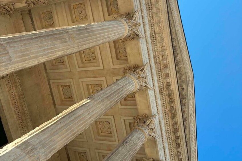A close-up of a building's ornate ceiling with a geometric pattern and classical columns. 1