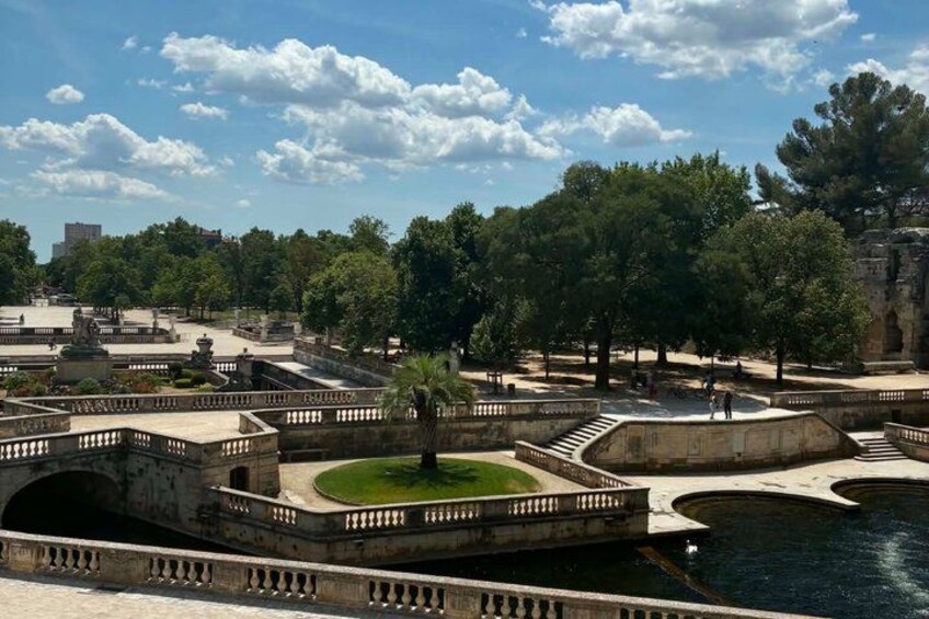 A park with a fountain, trees, and a stone bridge. 5
