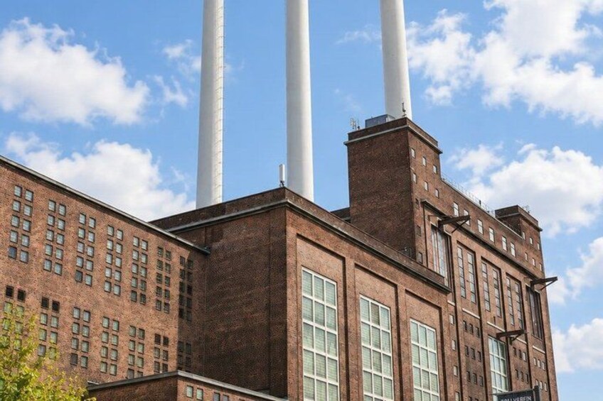A brick building with three tall chimneys and a clear blue sky. 2