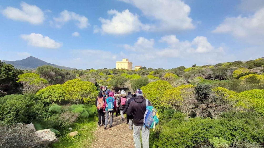 A group of hikers on a trail with a mountain and a building in the background. 2