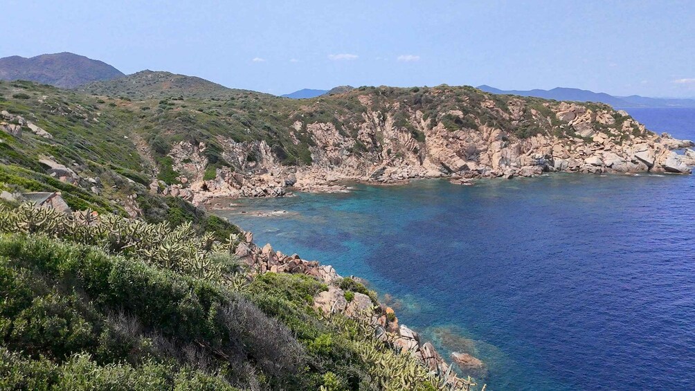 Paesaggio costiero con scogliere rocciose, mare blu cristallino e vegetazione rada. 2