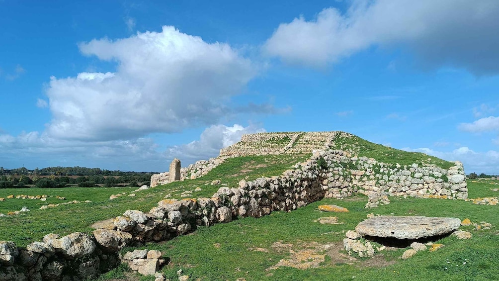 A stone ruin with a grassy hill in the background. 1