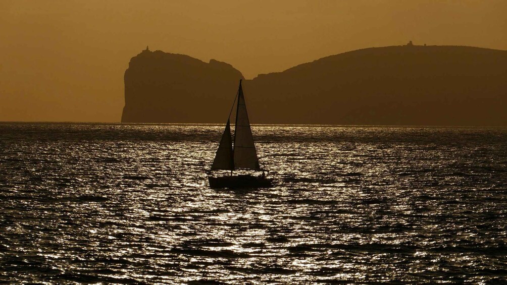 A sailboat on calm waters with a silhouette of a mountain in the background. 4