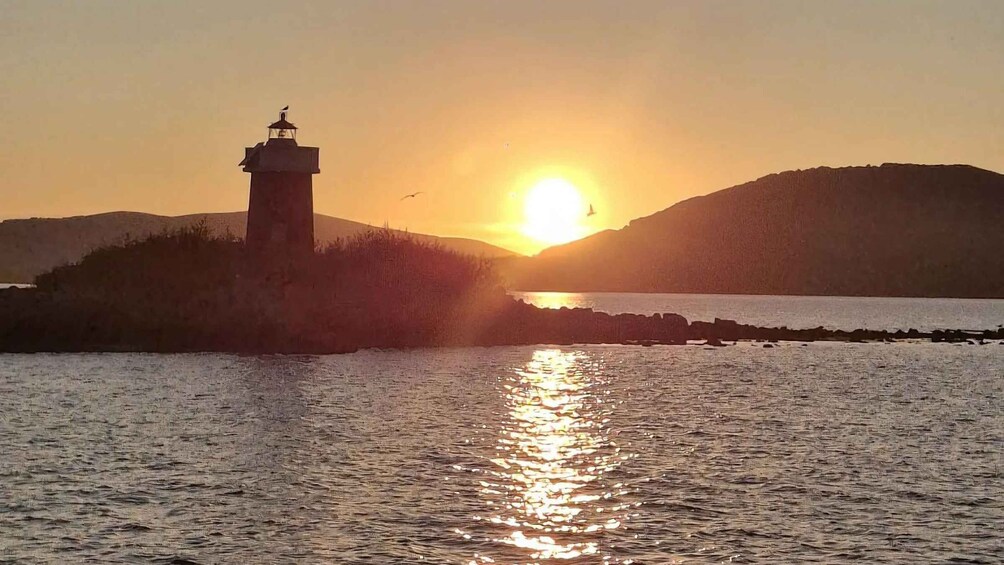 A sunset over a body of water with a lighthouse on a small island. 3