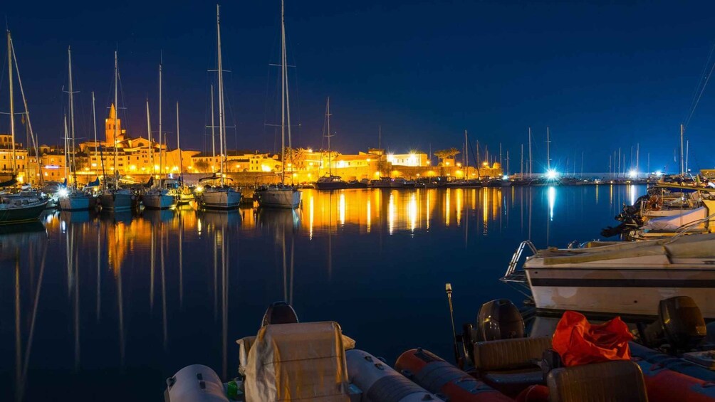 A marina at night with boats docked and city buildings in the background. 2