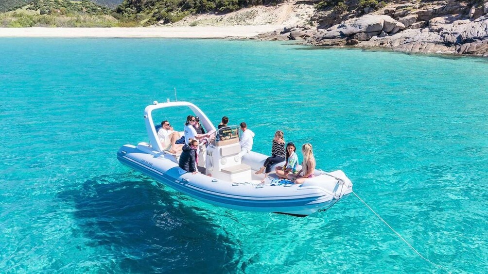A small inflatable boat on clear turquoise water with people on board. 5