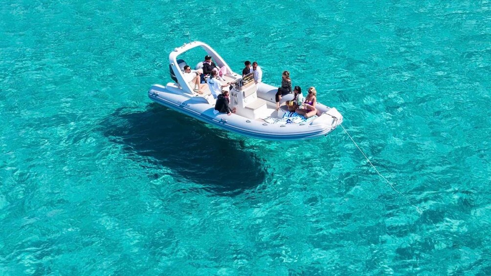 A small inflatable boat with people on it in clear turquoise water. 1