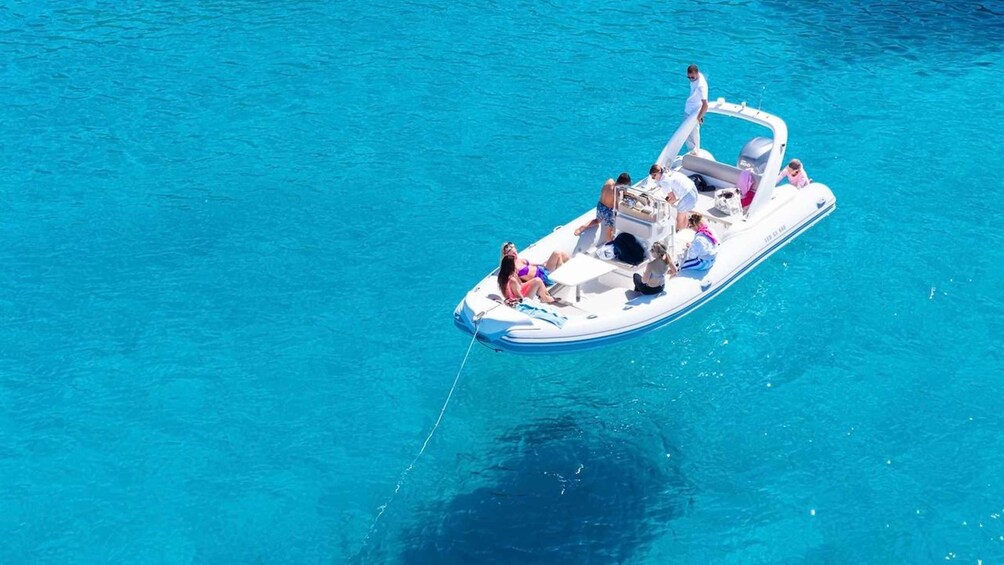 A small motorboat with several people on board, floating on clear blue water. 2