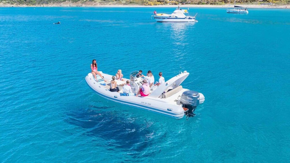 A group of people on a white motorboat with a Yamaha outboard motor, floating on clear blue water. 3