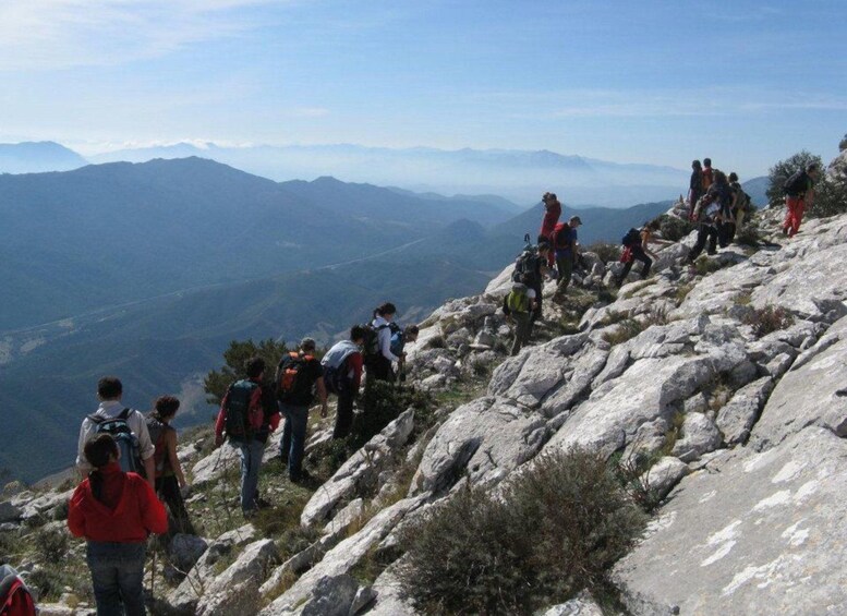 Hikers on a rocky mountain trail with a view of distant mountains. 1