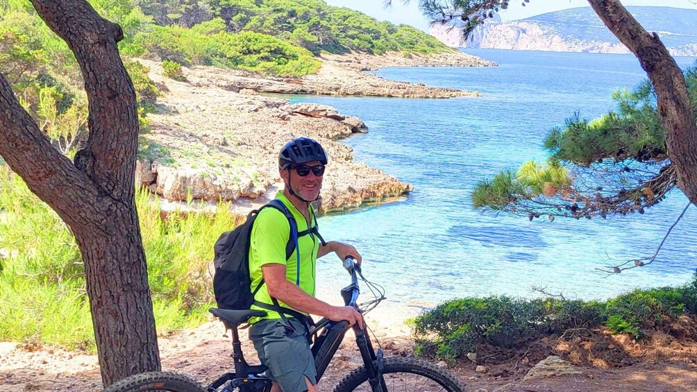 A person on a mountain bike near a body of water with rocky terrain and trees. 5