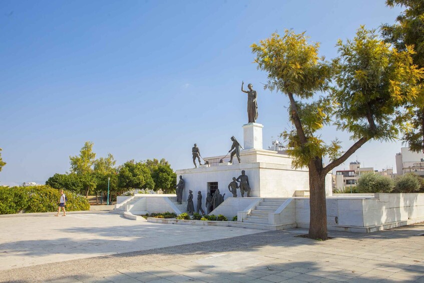 Une place publique ornée d’un monument comprenant des statues, entourée d’arbres et de bâtiments. 3