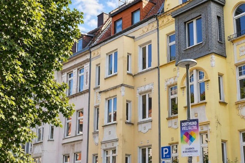 A row of multi-story buildings with a street lamp and a parking sign. 4