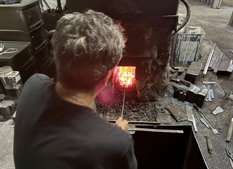 Una persona trabajando con un objeto metálico incandescente en una fragua. 2